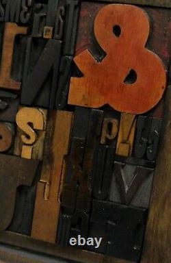 33 pcs. Vintage/antique letterpress in a stained wood frame with black stand